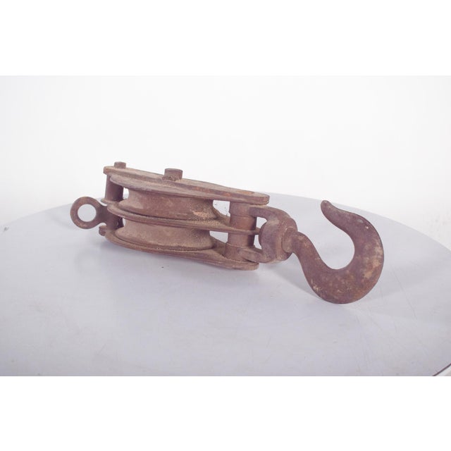 This antique Portuguese double pulley, crafted entirely in iron, is a robust example of traditional industrial and...