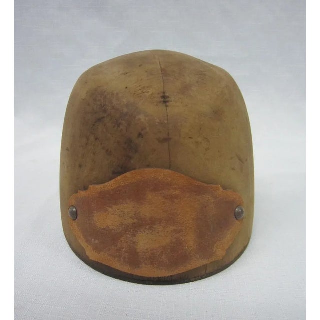 Unusual antique wood hat form with leather applique on front and back of form. Form is carved from a single block of wood.