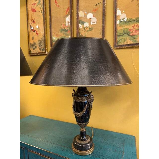 Pair of neoclassical urn-shaped table lamps in veined black marble, mounted with gilt bronze mounts—ram's head handles,...