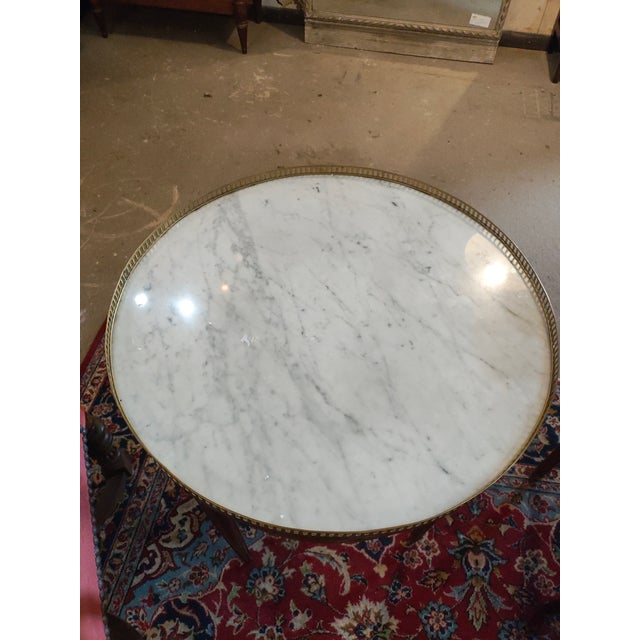 Elegant French Louis XVI style oval center table featuring a white marble top surrounded by a pierced brass gallery. The...