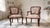 A charming pair of vintage Louis XV Style armchairs featuring carved wood frames in a rich walnut-toned finish, graceful...
