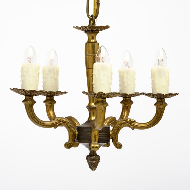 Petite chandelier from France made of solid bronze. This fixture features five candelabra arms and an acorn finial. This...