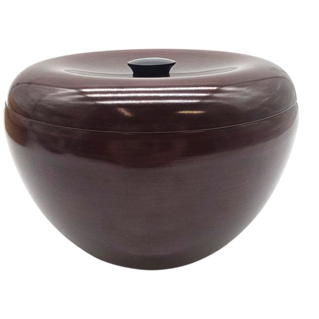 Smooth as silk spun from shadow, this vessel whispers restraint. Deep maroon lacquer curves around a quiet form, where...