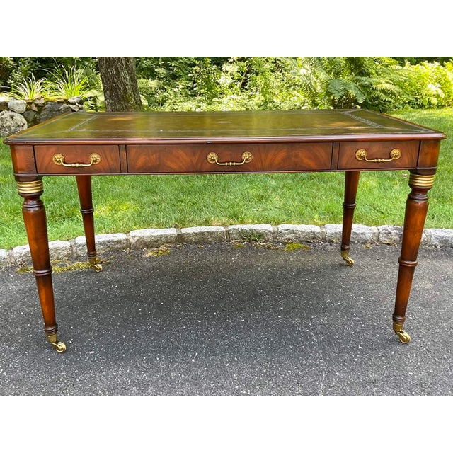A vintage Regency style mahogany writing desk with a rectangular brown tooled leather top and banded border, three drawers...