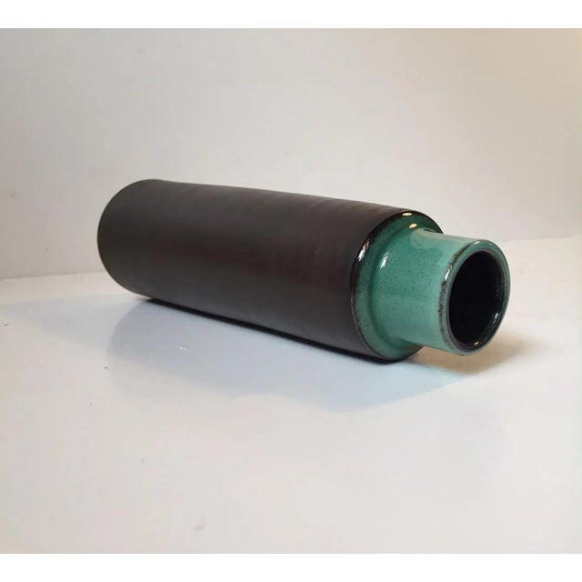 This Danish cylindrical vase comes in brown with a vibrant green glaze. It was designed and manufactured by Hyllested in...