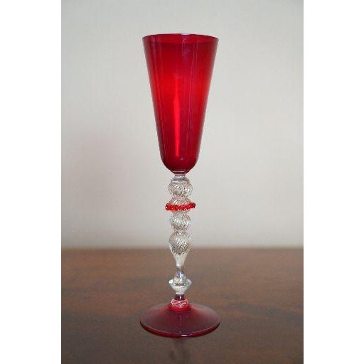 A striking vintage Murano art glass chalice featuring a tall ruby red trumpet-form cup, matching red foot, and a...