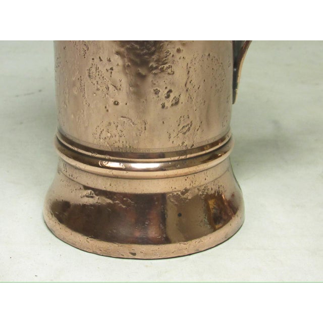 French polished copper half liter jug, c.1930. Having a long body with a decorative pitted appearance and a shapely...