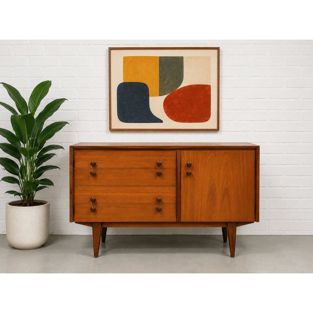 Petite Mid Century Modern Danish teak credenza featuring a warm richly grained teak exterior, tapered solid wood legs and...