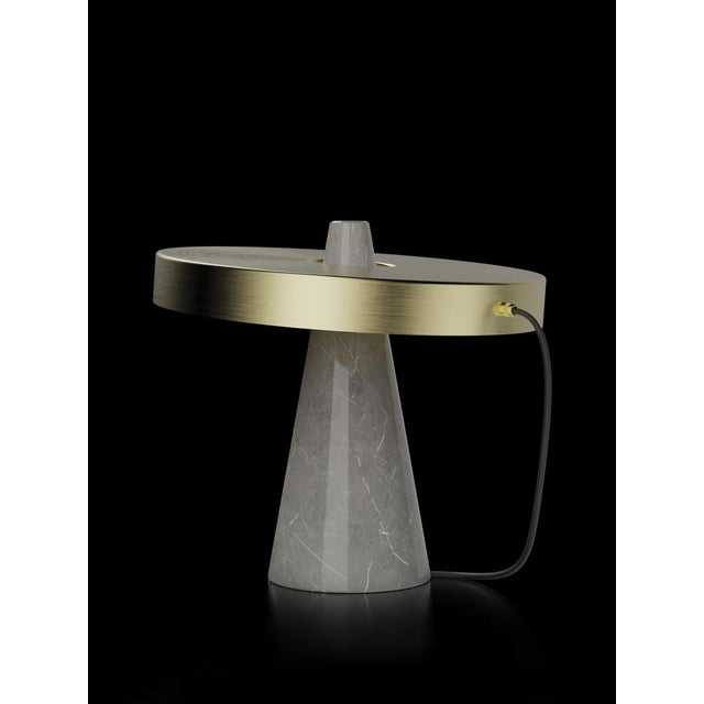Table lamp with grey stone base and brushed brass lightshade. The light shade is disconnected from the stone base and free...