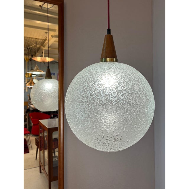The elegant glass and teak globe lamp from Doria impresses with its harmonious design and high-quality materials. The...