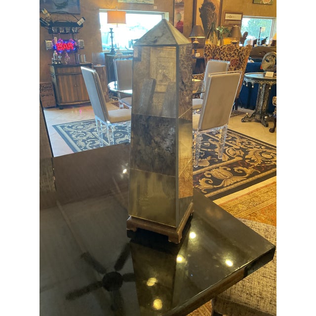Pair of Venetian-styled Mirrored Obelisks on rusticated wood made to look like metal raised platforms. The mirrors have a...