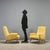 Two 1960s Italian-made armchairs with painted metal legs, brass tips, and a cushioned seat upholstered in yellow fabric....