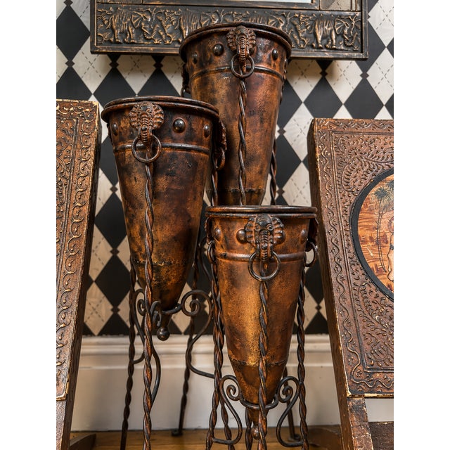 Set of three graduated sculptural metal floor vessels on twisted iron stands. The vessels feature tall conical forms with...