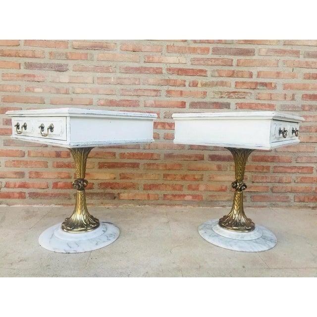 Elegant pair of neoclassical side tables, each featuring a square top with a single drawer. The wooden structures are...