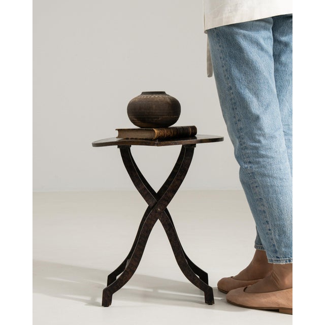 This piece presents as a candle holder/stand, distinguished by dark wrought iron, tripod X-form base. Originating in...