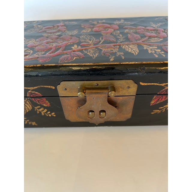 Lovely unusually long and narrow Chinoiserie box having black background with red and gold flowers, brass hinge and bun feet.