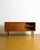 A compact 120 cm danish teak sideboard from the 1960s. Two sliding doors with carved rectangular handles flank a central...