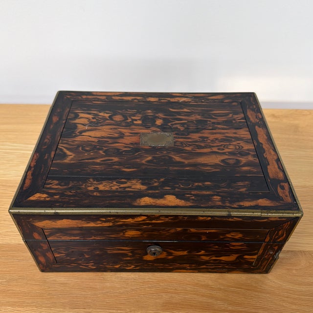 A handsome antique Victorian box featuring richly Coromandel wood in dramatic shades of deep brown, black, and warm amber....