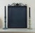 A salvaged slate chalkboard set in a dark iron frame, topped with a scrolled wrought iron crest and cross, and surrounded...