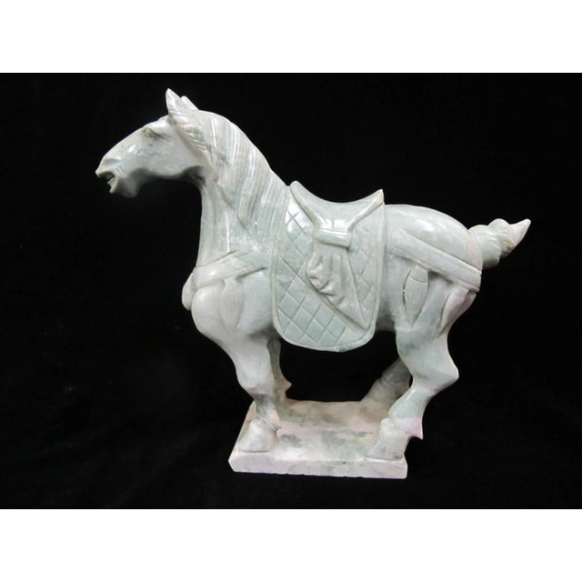 Chinese carved soap stone horse figurine standing on an integral rectangular base, featuring a detailed saddle and bridle...