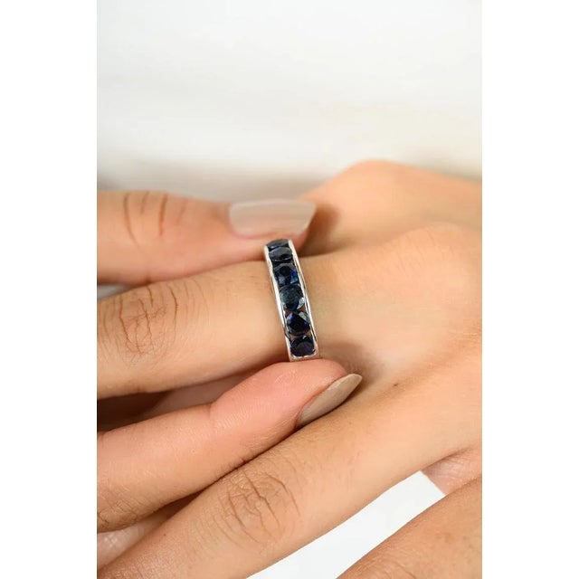 This Blue Sapphire Eternity Band Ring is expertly crafted in 925 sterling silver. The band features a sleek channel...