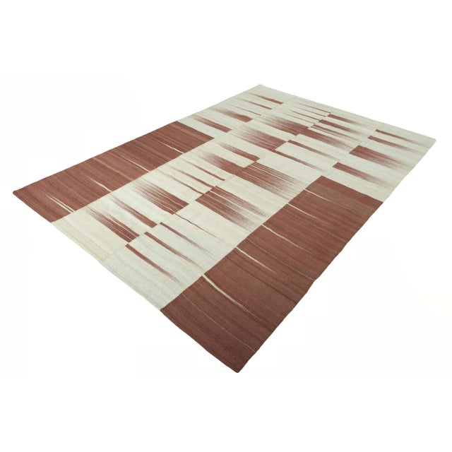 This handwoven designer kilim rug, made from high-quality virgin wool, impresses with a contemporary design in warm...