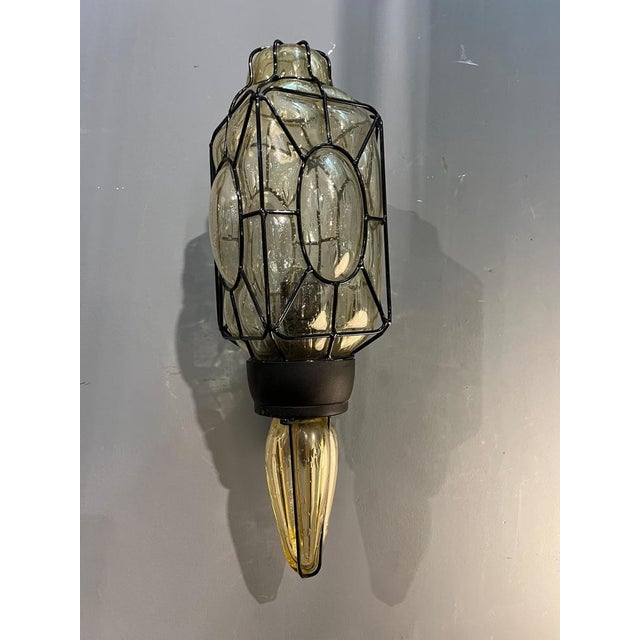 An elegant Murano glass wall light, crafted in Italy in the 1980s. The light fixture is composed of transparent blown...