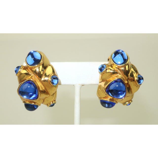 A beautiful pair of 1980's Antigona Paris gold plated clip-on earrings accented by sapphire blue poured glass cabochon...