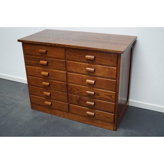 These apothecary cabinets were made circa 1950s in Germany. They features 12 drawers with oak handles. The interior...