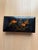 The flat, rectangular box with rounded corners is made of wood and coated all around with high-gloss black lacquer. The...
