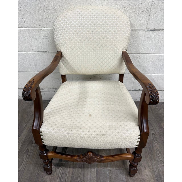 This is a stunning vintage Spanish Revival walnut armchair featuring hand-carved acanthus arm terminals, a carved shell...