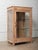 A charming vintage wooden and glass display cabinet featuring two glass sides, a glass front door, and a single interior...