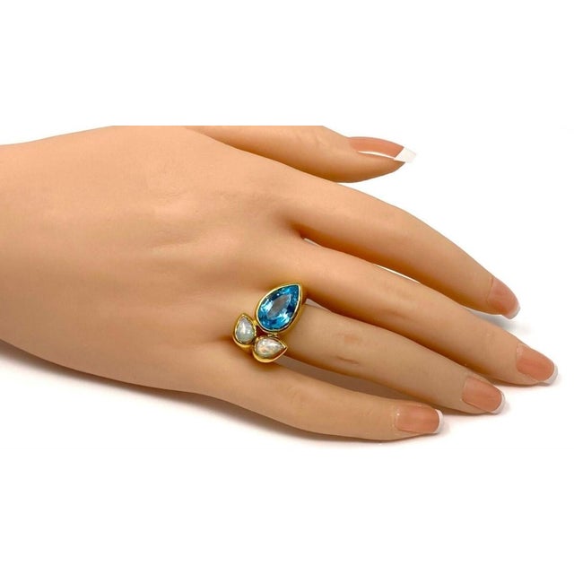 This Blue Topaz & Fire Opal 18k Yellow Gold Floral Ring in size 7.5 is a fine jewelry piece that exudes elegance and...