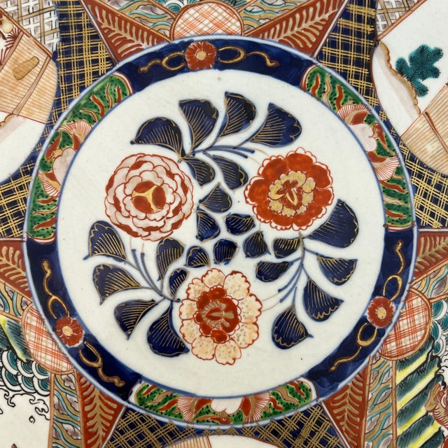 Large Asian ceramic platter. The platter depicts figures and dragons and the out of doors. It has markings on the bottom.