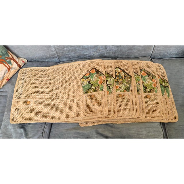 Two boxes of four. Total of Eight rattan placemats. Each has a pocket with a folded napkin and a button with flap at the...