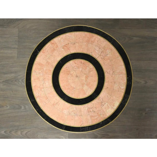 A post modern light pink tessellated stone and brass inlay hourglass shaped side table. Minor signs of damage shown. 16.5”...