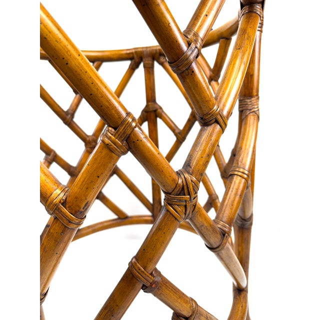 A sculptural rattan table base in the style of McGuire, featuring an intricate geometric lattice construction with tightly...