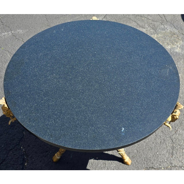 An elegant French Neoclassical-style gueridon table featuring a striking circular black granite top raised on a sculptural...