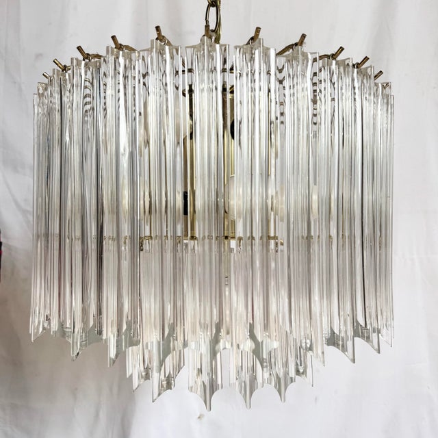 A striking Art Deco two-tier chandelier featuring cascading lucite prisms suspended from a warm brass framework. The...