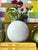 This white ceramic vase presents a minimalist aesthetic with its spherical form and smooth surface. Its clean,...