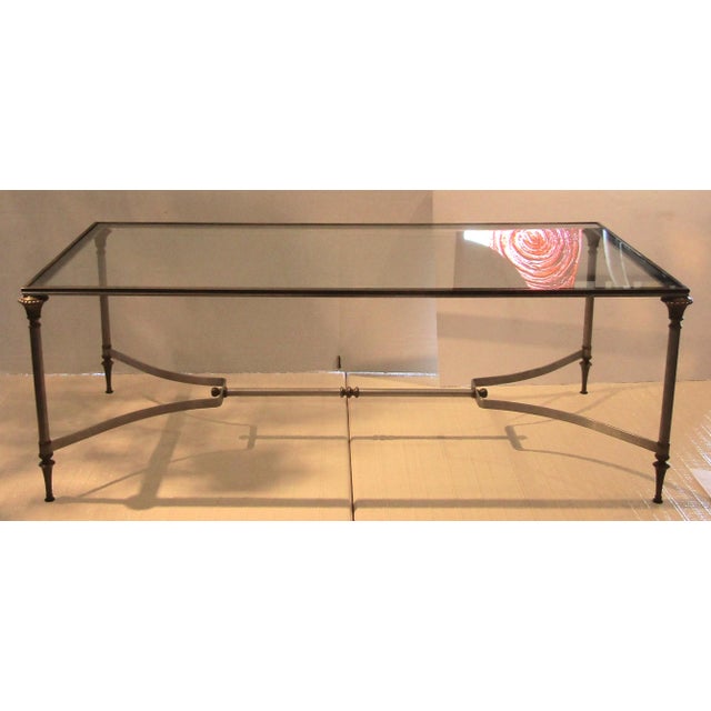 The Maison Jansen Brass and Steel Glass Top Cocktail Table from the 1960s is a vintage piece of furniture that exudes...