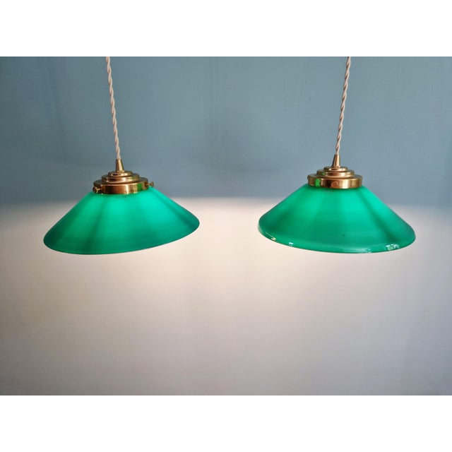 Pair of art deco style conical green opaline glass pendant lights with brass mounts. shades signed "emelite". each pendant...
