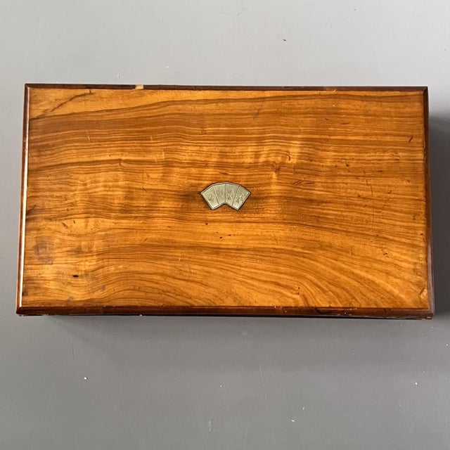 A handsome antique poker set dating to the 1920s, housed in a veneered burlwood gaming box with silver-hued playing card...