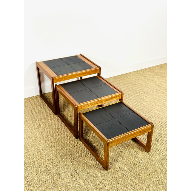 An elegant set of three nesting tables in solid teak with black glazed ceramic tiles, typical of 1960s scandinavian...
