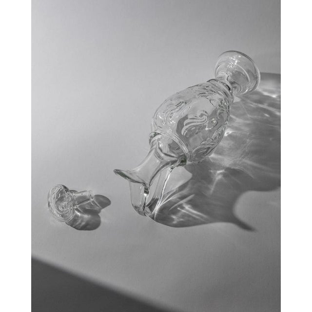 This vintage pressed glass decanter from 1960s Italy is a refined bar accessory crafted in clear sculptural glass with a...