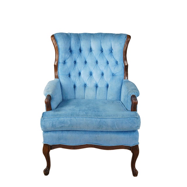 Antique French arm chair featuring a blue velvet tufted upholstery with fauteuil rolled arms, wingback, and cabriole legs....