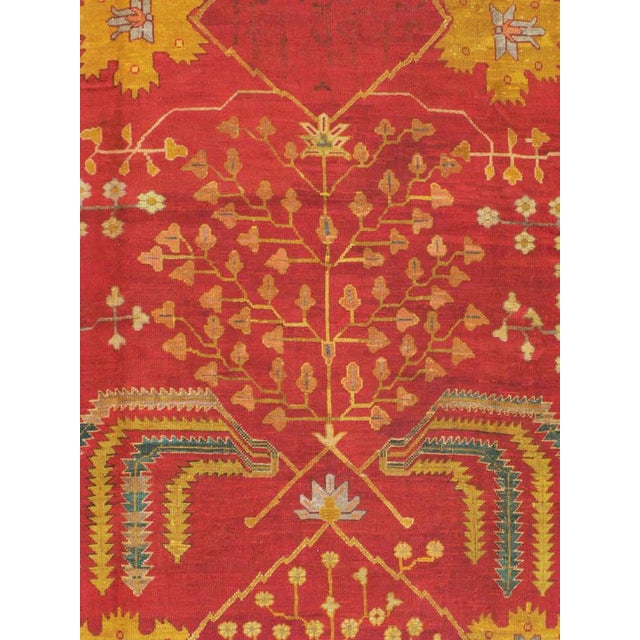An antique Turkish Oushak carpet from the first quarter of the 20th century. A goldenrod border encompasses a crimson red...