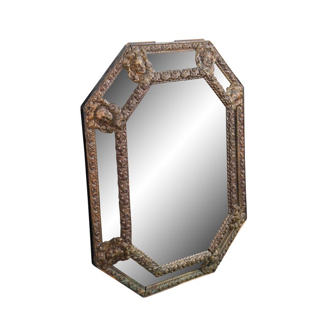 An antique French Louis XIII style octagonal mirror with ornate figural brass repousse showcasing roses and cherub faces....