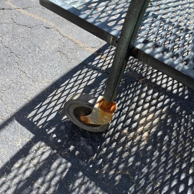 Striking mid-century modern tiered bar cart crafted in black wrought iron, attributed to the style of Salterini for...