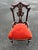 Charming carved wood side chair featuring an ornate open back and turned legs, paired with rich red upholstery that adds...
